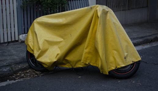 A yellow tarp cover over a parked motorcycle on the street